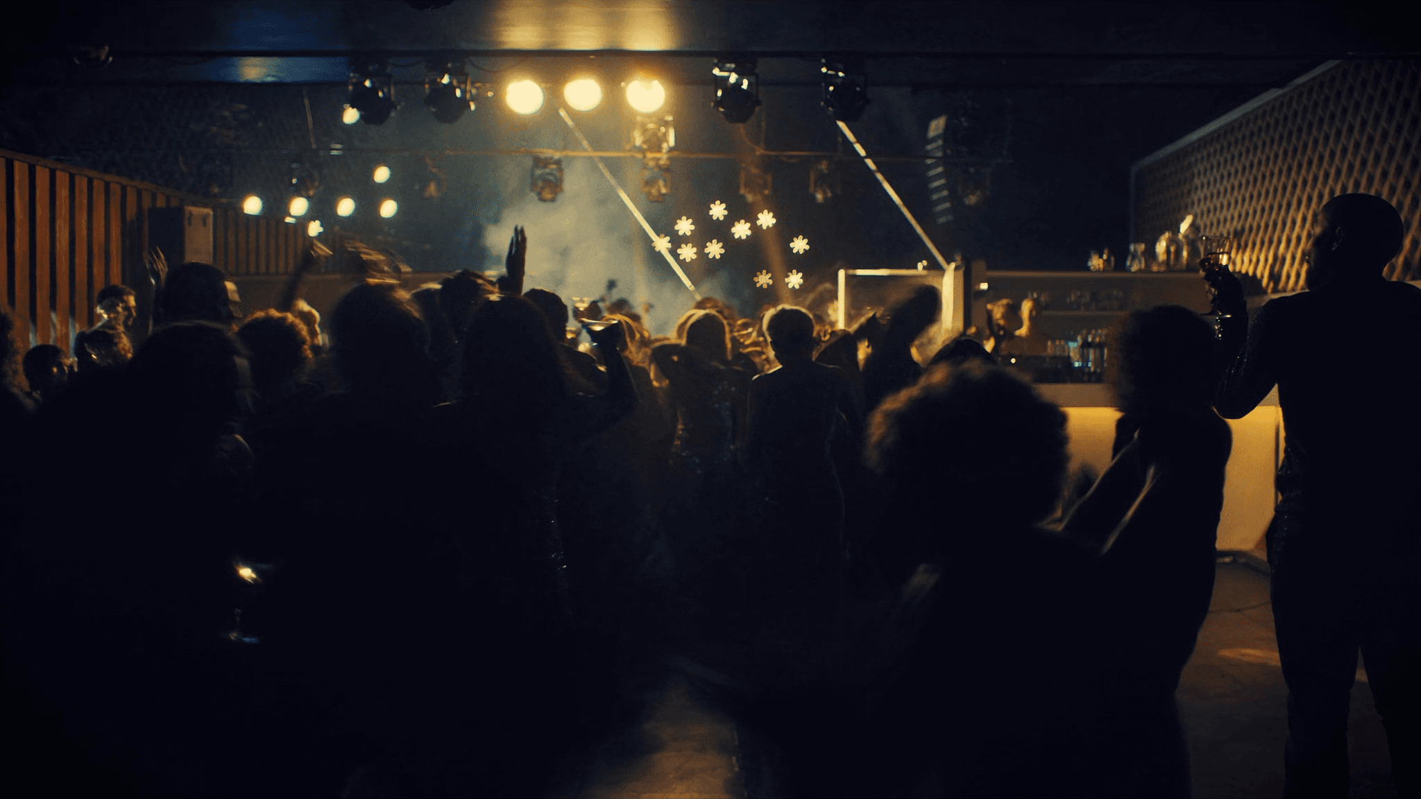 An energized NYX crowd silhouetted against warm stage lighting on the main floor.