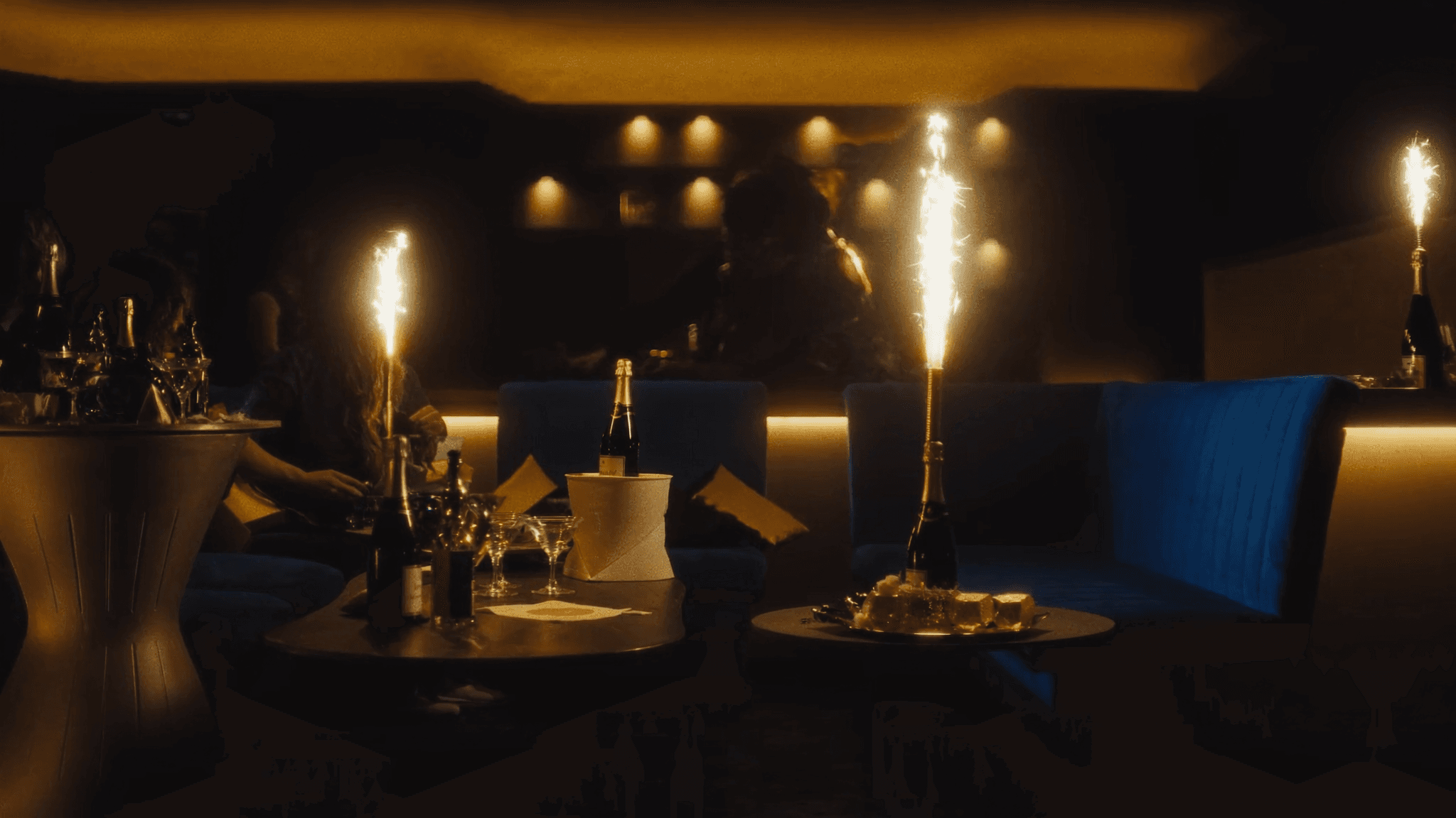 A NYX VIP champagne booth — blue velvet seating, bottle service on ice, lit sparklers.