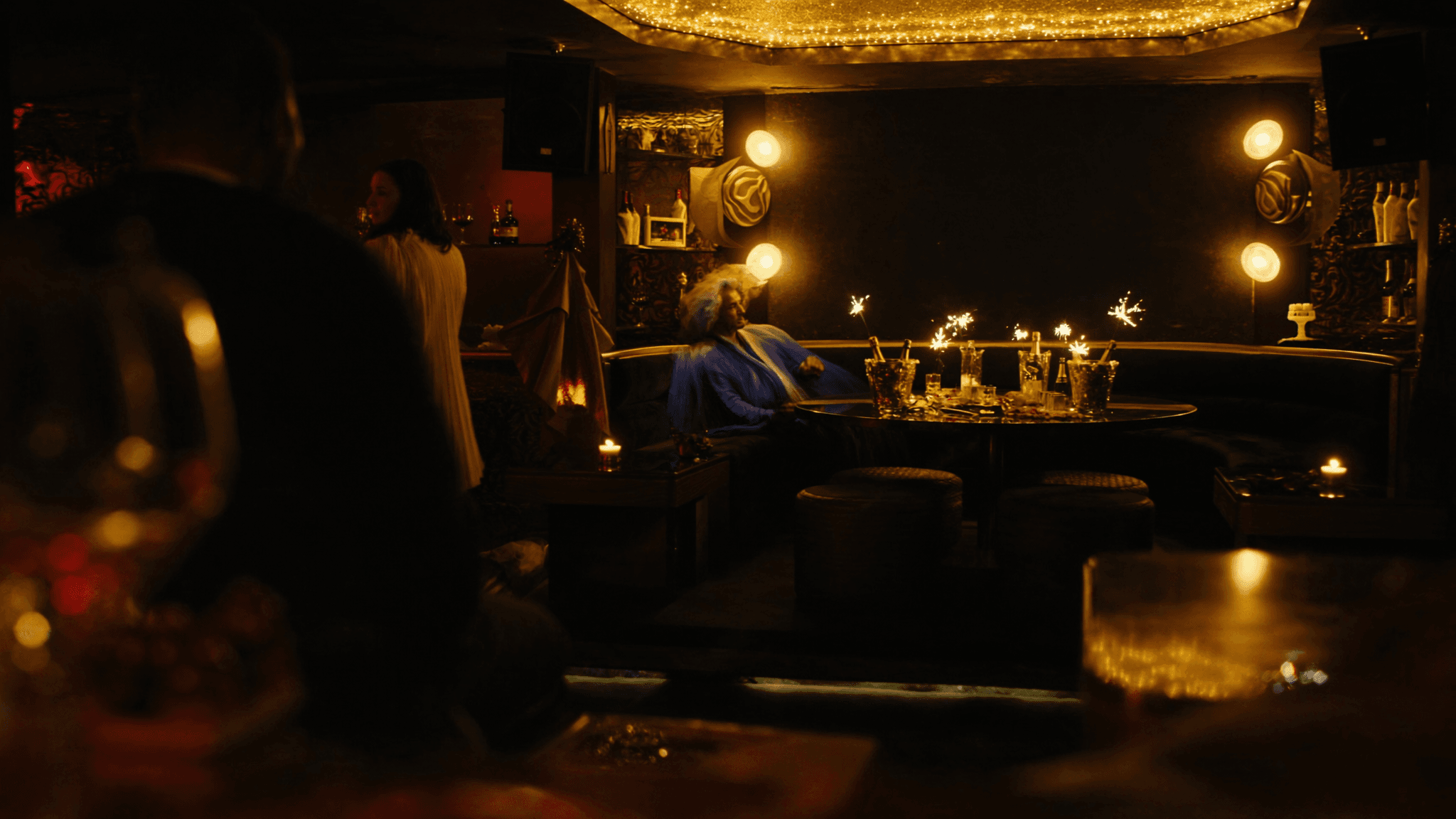 An intimate NYX lounge corner wrapped in warm bokeh light and candlelit tables.